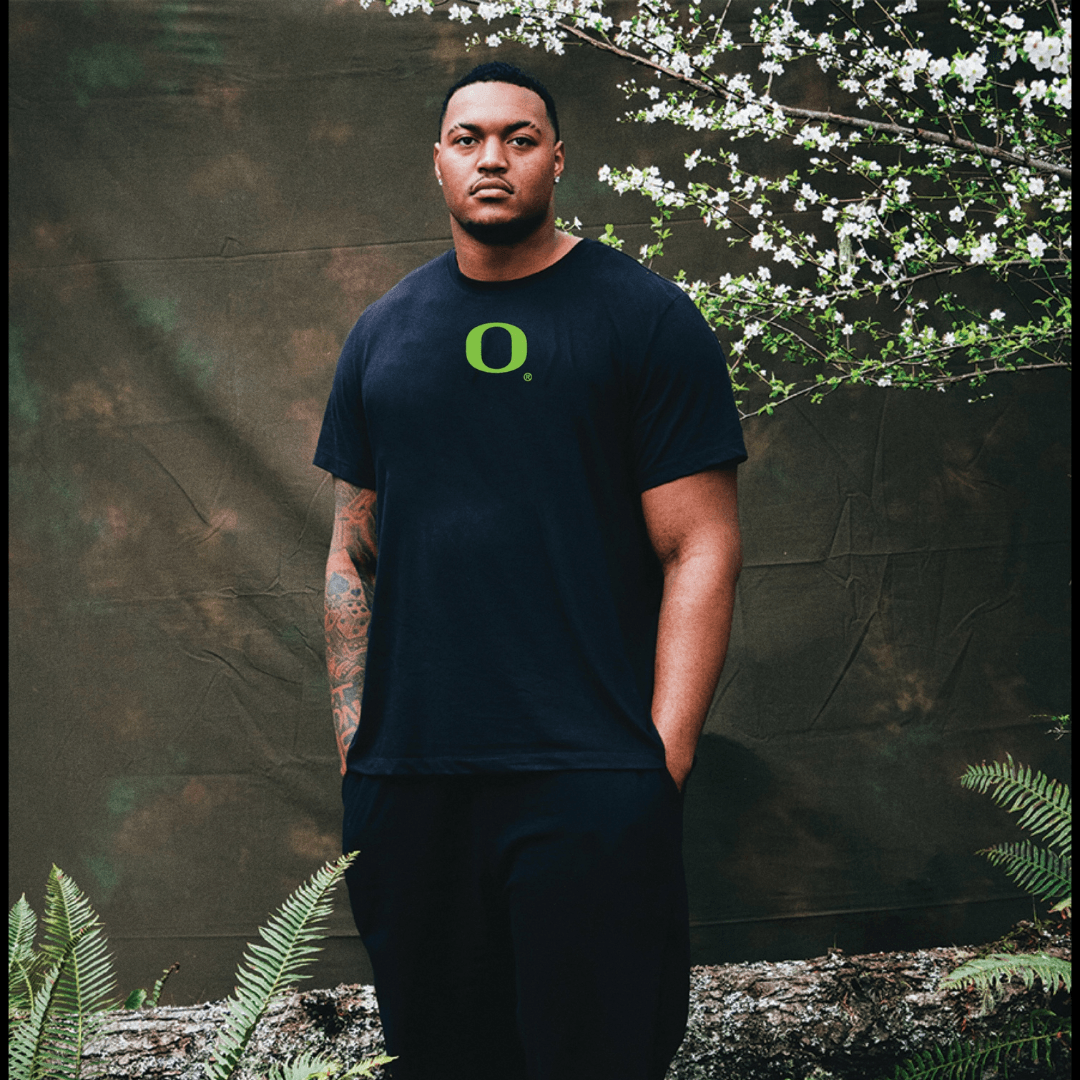 Ziyare Addison wearing a black DOAF t-shirt with a green logo against a natural background