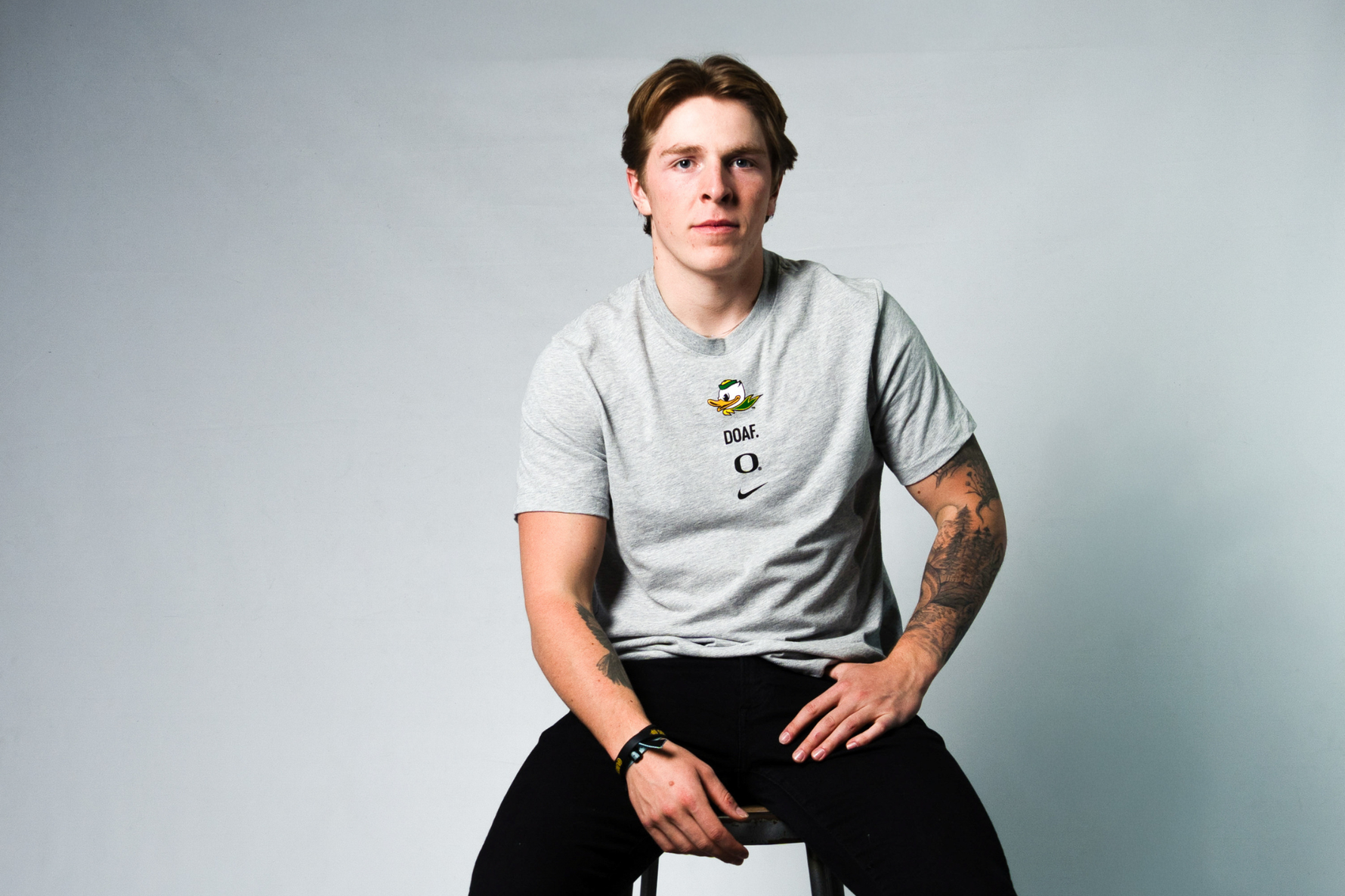 Atticus Sappington wearing a light gray DOAF t-shirt with a logo on a plain background