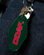 Green keychain tag with red 'DOOF' logo on a dark fabric background