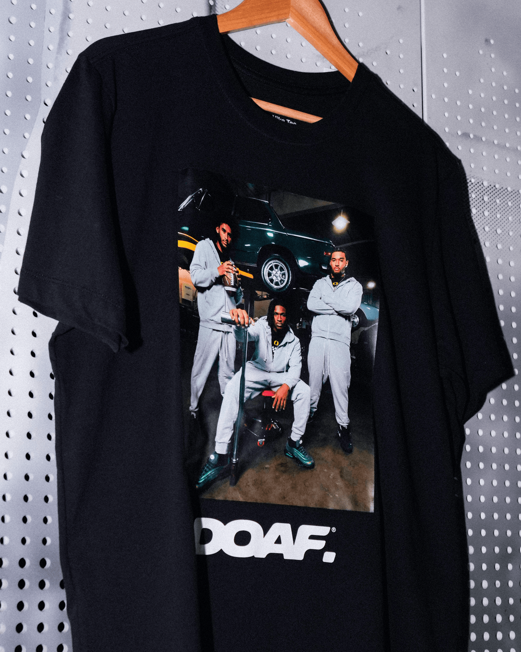 DOAF Tee featuring Dante Moore, Dakorien Moore, and Matayo Uiagalelei hanging up in the locker room. 