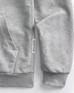 Detail of the brand label and sleeve of the Speedway Gray hoodie on a white background