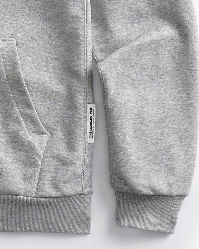 Detail of the brand label and sleeve of the Speedway Gray hoodie on a white background