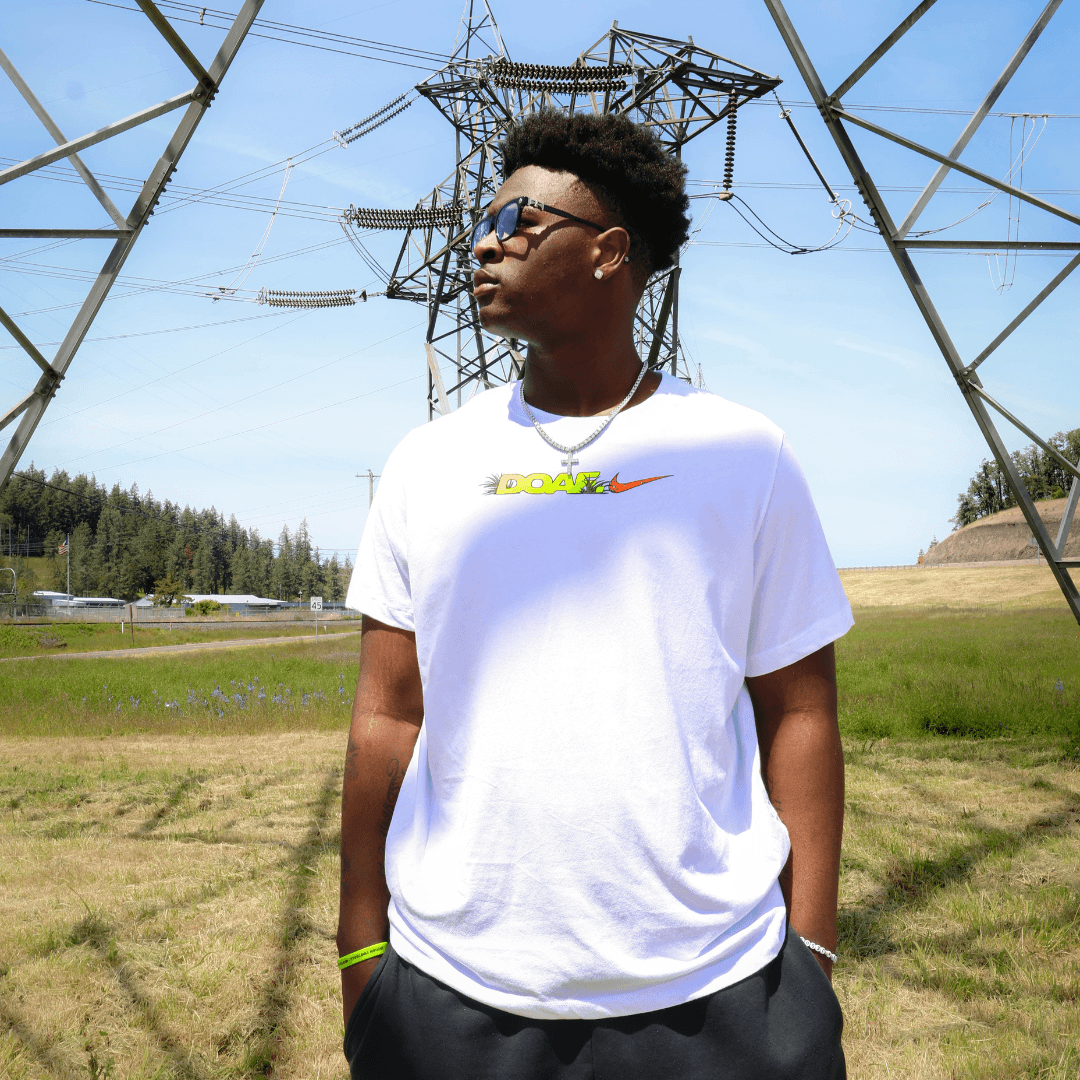 Tony Cumberland wearing a white DOAF t-shirt with a logo in an outdoor setting with power lines in the background