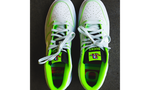 The Nike Dunk Low “Oregon” Player Edition. The shoe features a subtle tone-on-tone combination of off-white split suede quarter panels and toe boxes, and overlays of light grey tumbled leather accented by electric green stitching throughout, which also outline the white leather Swoosh branding. Additional branding, as well as another color pop, are provided by an electric green tongue tag sporting a multi-colored Duck head logo over all caps “DUCKS” branding.